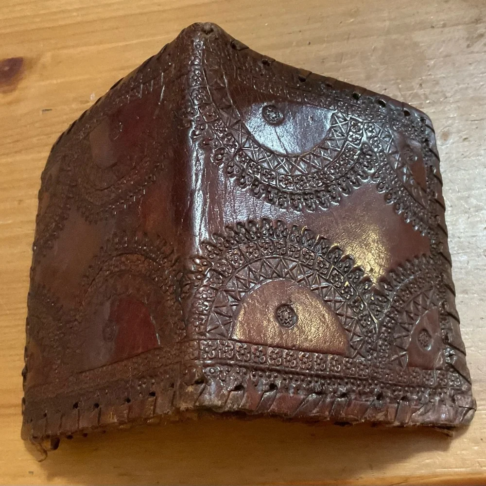 Hand crafted tooled mens leather design bifold wallet laced stitching around it.
